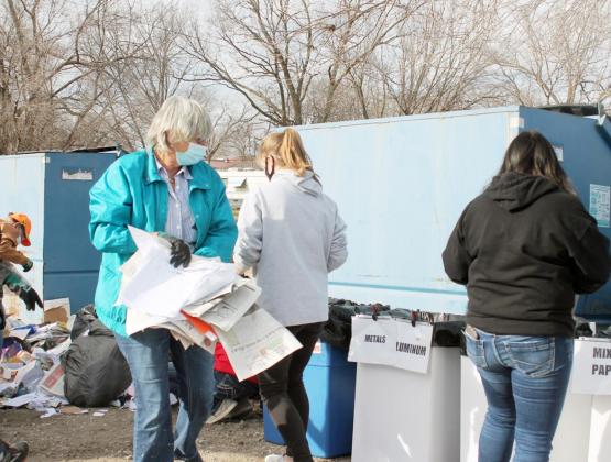 TWO TECUMSEH CITY COUNCIL MEMBERS got involved in sorting items from the city’s recycling bins. Lorie Topp carries papers to the sorting area while, in the background, Jim Reed can be seen going through items still on the ground. Ann Wickett/Chieftain