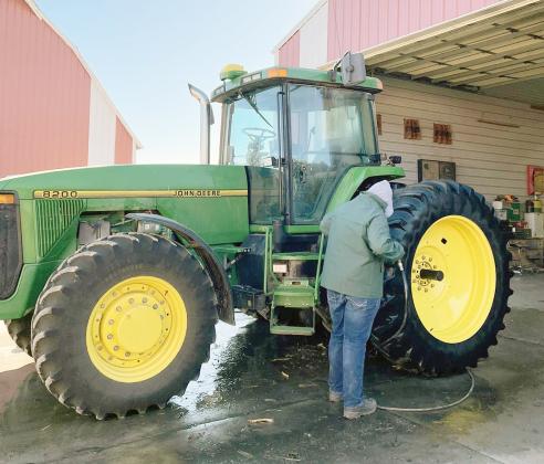 KAYDEN BADERTSCHER gets busy cleaning this farm tractor for one of the JCC FFA’s ag detailing customers.
