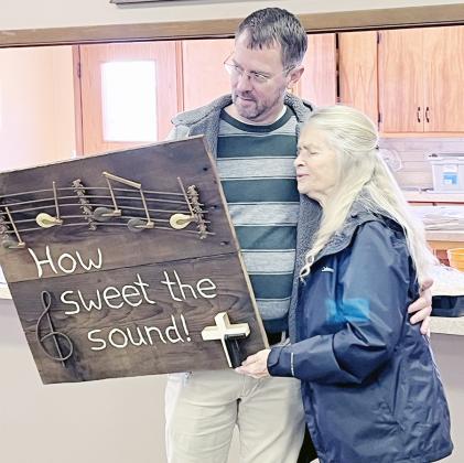 Velda Koehler, right, was honored for her dedication at St. Paul’s (Maple Grove) United Church of Christ for 50 years of playing the organ for worship. Her nephew, Jon Koehler, left, presented Velda with a wall hanging he made from parts of a piano.