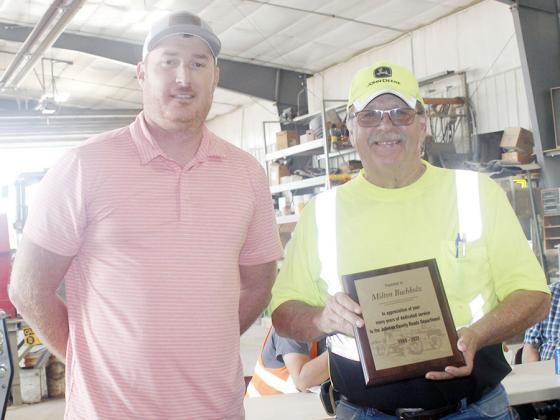 ON HIS 70TH BIRTHDAY, MILTON BUCHHOLZ, right, received a plaque for his 34 years of dedicated service to the Johnson County Roads Department from County Roads Superintendent Matt Schaardt, left.